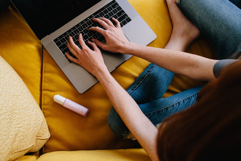 Someone typing on a laptop with a COOLA product to the left